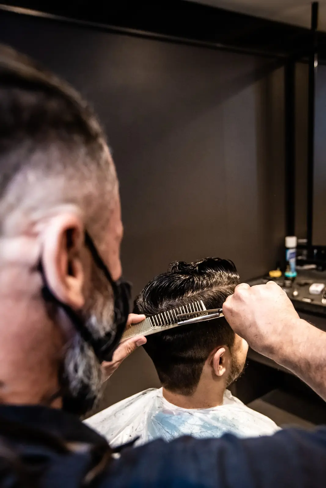 Barber der klipper en kunde med saks og kam