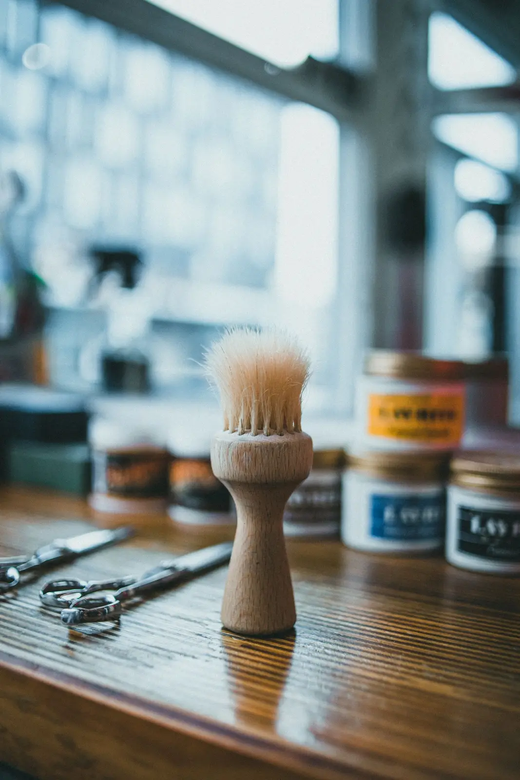 Barberkost, sakse og krukker på et træbord